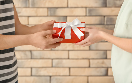 Happy young couple with gift box near brick wall, closeupの写真素材