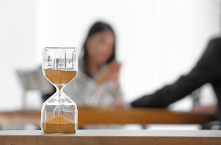 Hourglass and blurred people on background. Time management concept