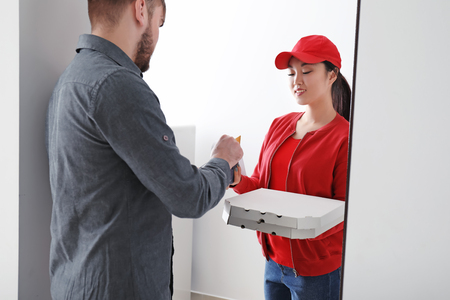 Young man receiving order from courier at doorway. Delivery serviceの写真素材