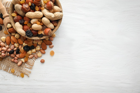 Bowl with various tasty nuts and dried fruits on wooden table