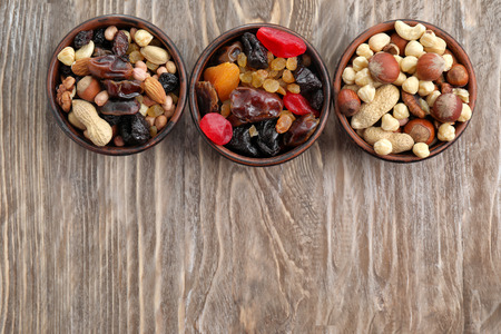 Bowls with mix of dried fruits, berries and nuts on wooden background, top viewの写真素材