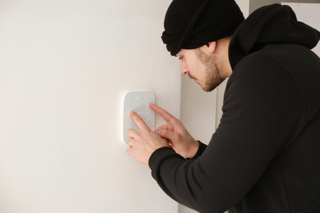 Thief typing password on alarm system, indoorsの写真素材