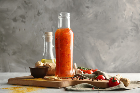 Bottle with tasty sauce and vegetables on wooden boardの写真素材