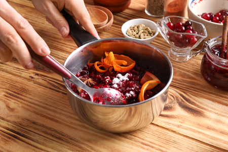 Woman preparing delicious cranberry sauce at tableの写真素材