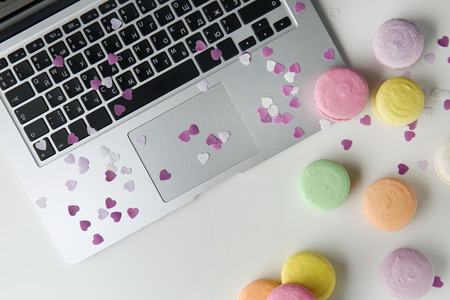 Tasty colorful macarons with laptop on white backgroundの写真素材