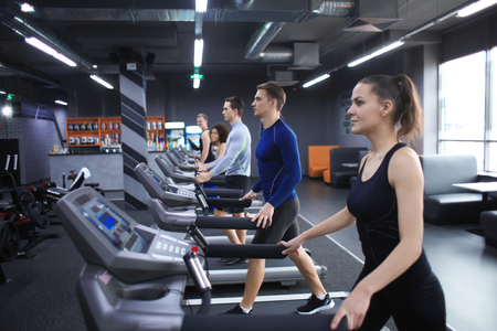 Young people running on treadmill in gymの写真素材