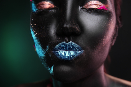 Portrait of beautiful young woman with surreal makeup on dark background, closeupの写真素材