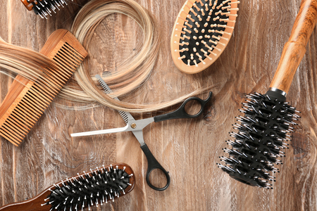 Flat lay composition with hairdresser's tools and strand of blonde hair on wooden backgroundの写真素材