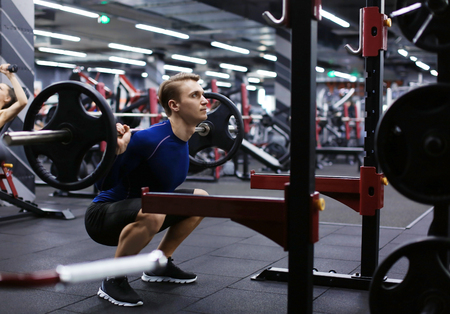 Athletic man training with barbell in modern gymの写真素材