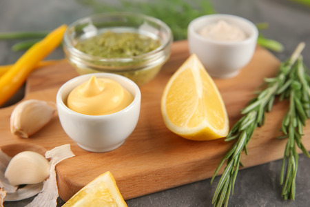 Bowls with different sauces on wooden board, closeupの写真素材