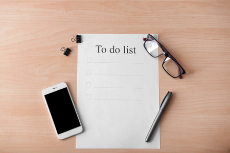 Empty to-do list with phone on wooden backgroundの写真素材