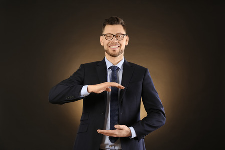 Young businessman holding something on color backgroundの写真素材