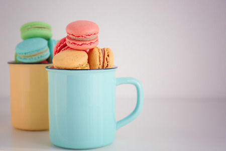 Metal cups with tasty colorful macarons on light backgroundの写真素材