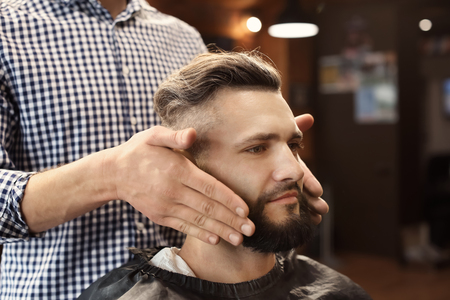 Professional barber working with client in hairdressing salonの写真素材