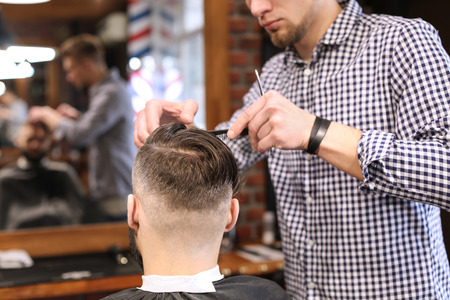 Professional barber working with client in hairdressing salonの写真素材