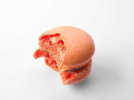 Tasty orange macaron with bite mark on white backgroundの写真素材