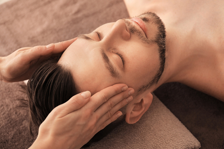 Young man receiving massage at spa salonの写真素材