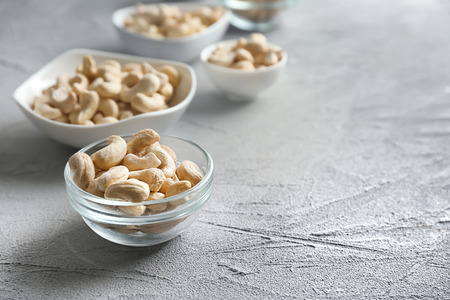 Bowls with tasty cashew nuts on light backgroundの写真素材