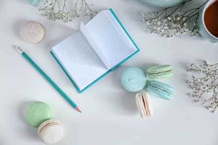 Composition with tasty colorful macarons and notebook on white backgroundの写真素材