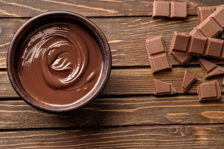 Tasty melted and solid chocolate on wooden background, top view