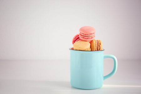 Metal cup with tasty colorful macarons on light backgroundの写真素材
