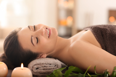 Young woman relaxing on massage table at spa salonの写真素材