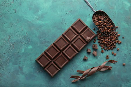 Delicious chocolate bar, shavings and coffee beans on tableの写真素材