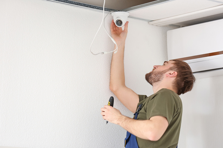 Electrician installing security camera indoorsの写真素材