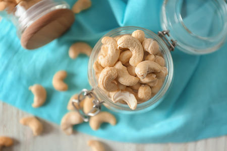 Glass jar with tasty cashew nuts on table
