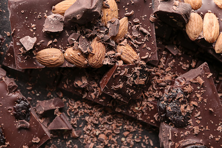Pieces of chocolate with almonds and dried fruits on tableの写真素材