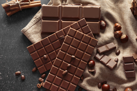 Tasty chocolate, hazelnuts and coffee beans on table, top view