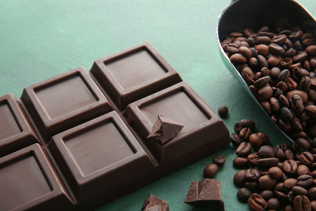 Delicious chocolate bar and coffee beans on tableの写真素材