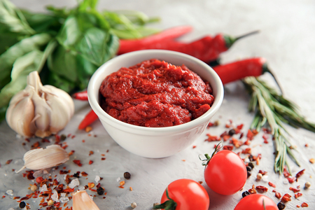 Bowl with red sauce and vegetables on grey backgroundの写真素材