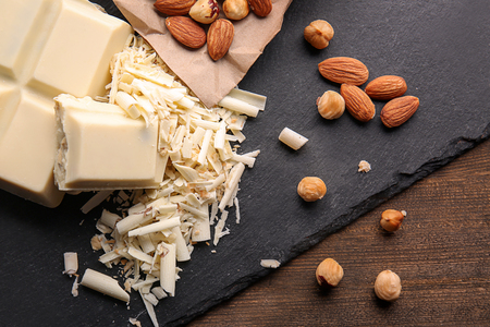 Slate plate with white chocolate curls and nuts on tableの写真素材