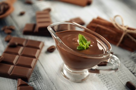 Gravy boat with tasty molten chocolate on wooden tableの写真素材