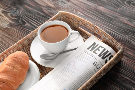 Tray with newspaper and cup of tea on wooden backgroundの写真素材