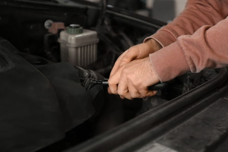 Auto mechanic repairing car in service center, closeup