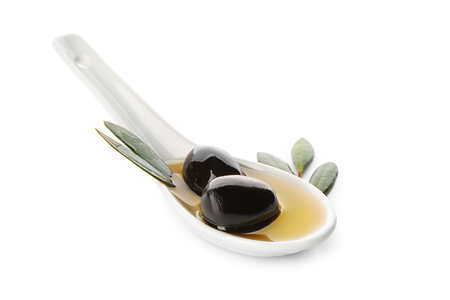Spoon with black olives and oil on white backgroundの写真素材