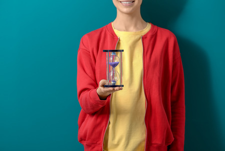 Woman holding hourglass on color background. Time management conceptの写真素材