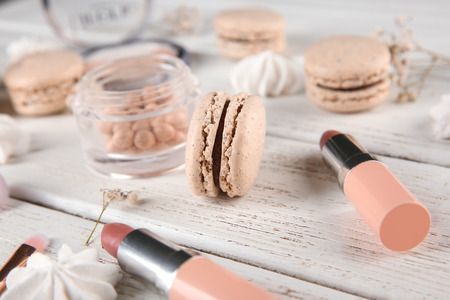 Tasty macaron and makeup products on wooden tableの写真素材