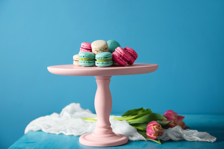 Dessert stand with tasty macarons on table against color backgroundの写真素材