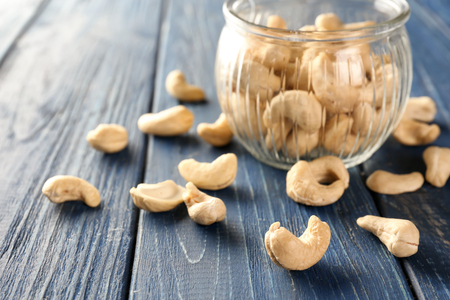 Tasty cashew nuts and glass jar on wooden backgroundの写真素材