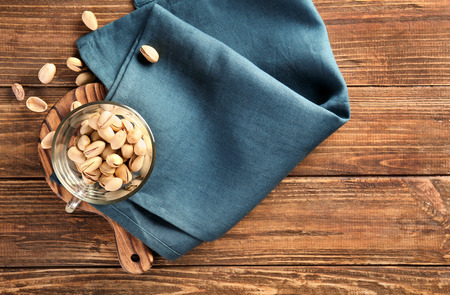 Glass cup with tasty pistachios on table, top viewの写真素材