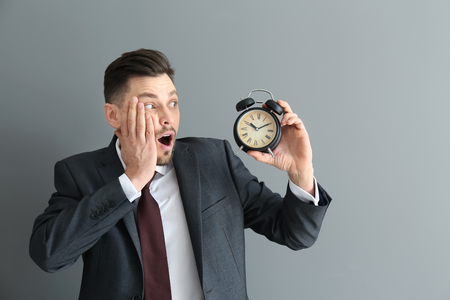 Businessman with alarm clock on gray background. Time management conceptの写真素材
