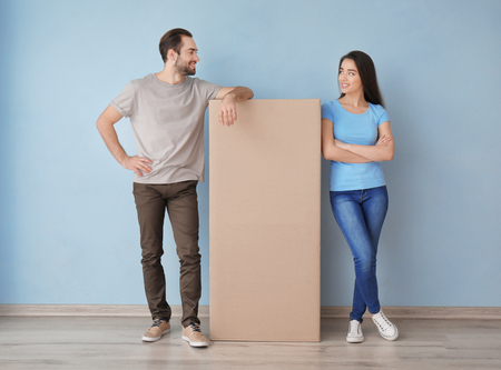 Young couple with box indoors. Moving into new house