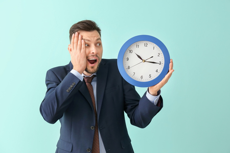 Businessman with clock on color background. Time management conceptの写真素材