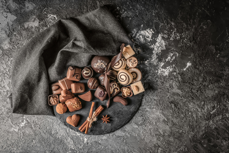 Slate plate with different tasty chocolate candies on textured tableの写真素材