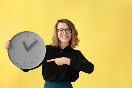 Mature woman with clock on color background. Time management conceptの写真素材