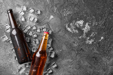 Fresh beer in glass bottles and ice cubes on gray backgroundの写真素材