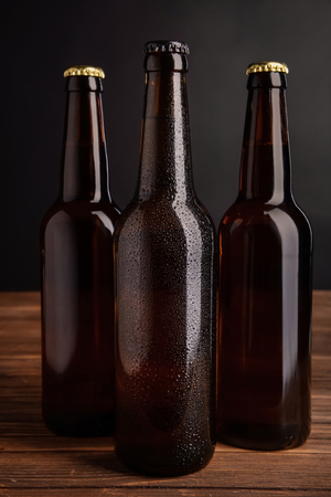 Fresh beer in glass bottles on table against dark backgroundの写真素材